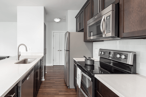 A modern kitchen with dark wood cabinets and stainless steel appliances.