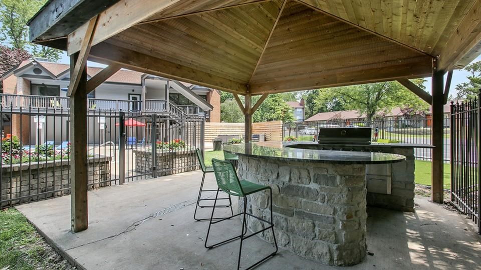 A patio with a bar and chairs under a wooden roof.