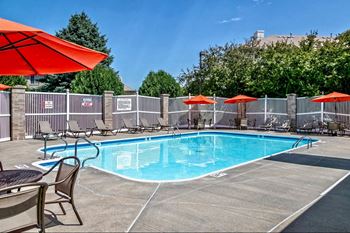 the swimming pool at our apartments with chairs and umbrellas