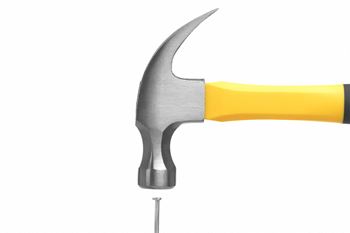 a hammer with a yellow handle hitting a nail
