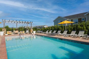 a swimming pool with lounge chairs and a house in the background