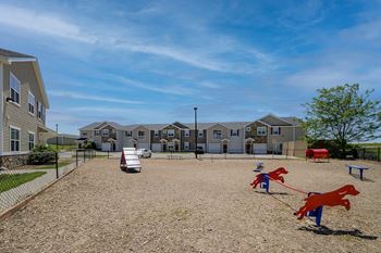 a playground with two horses on a leash in front of apartment buildings