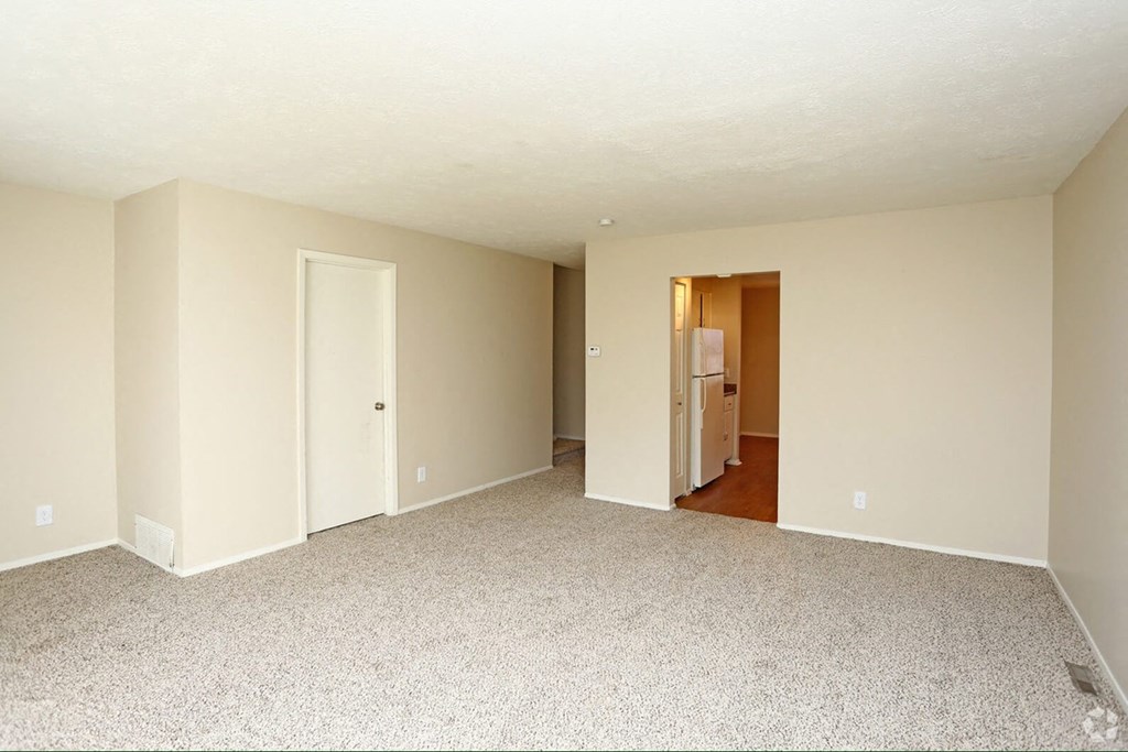 an empty living room with white walls and carpeting