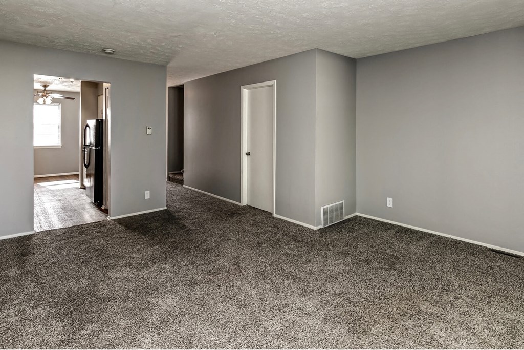 an empty living room with gray walls and carpet