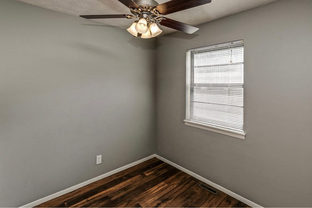 an empty bedroom with a ceiling fan and a window