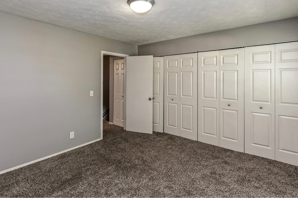 a bedroom with white closets and a carpeted floor