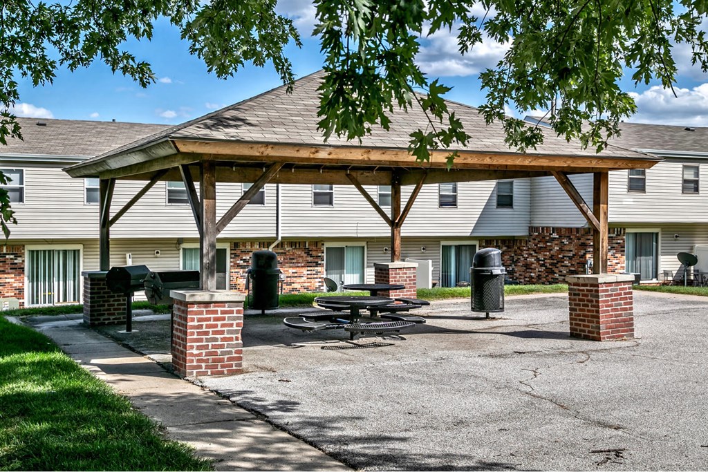 a pavilion with a picnic table in front of a building