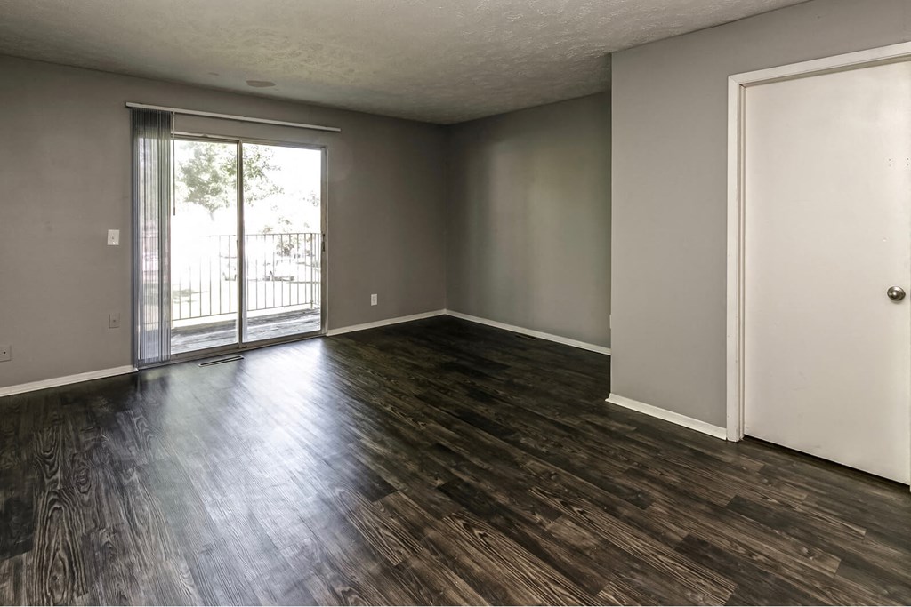 an empty living room with wood floors and a sliding glass door
