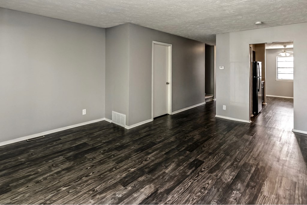 the living room and dining room of an empty house with wood floors