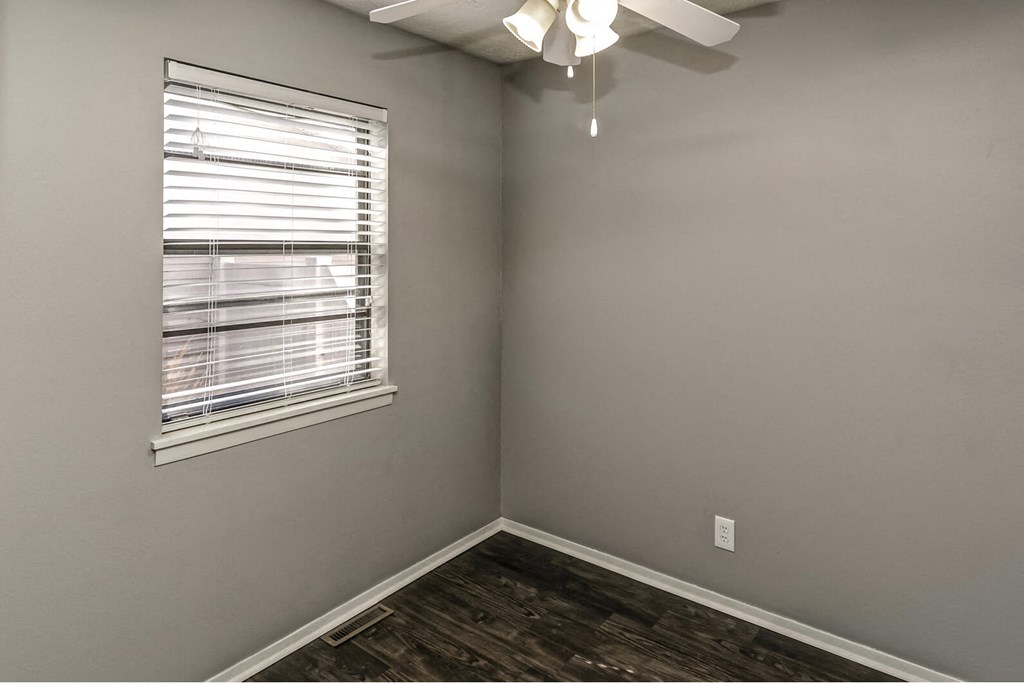 an empty room with a window and a ceiling fan