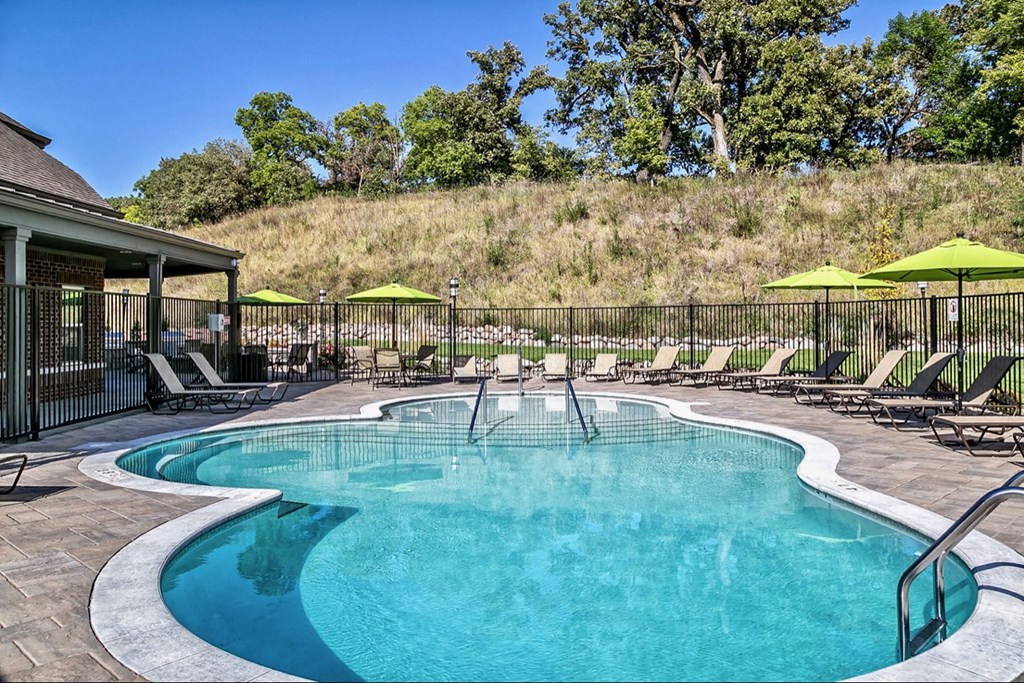 a resort style pool with chairs and umbrellas next to a house