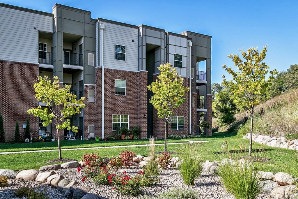an exterior view of an apartment building with grass and trees