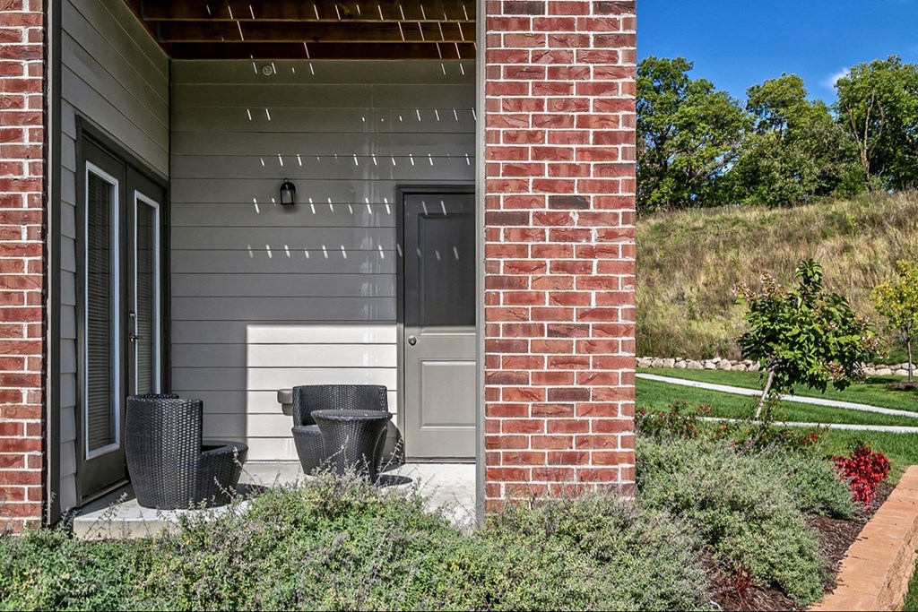 front porch of a home with two wicker chairs and a door