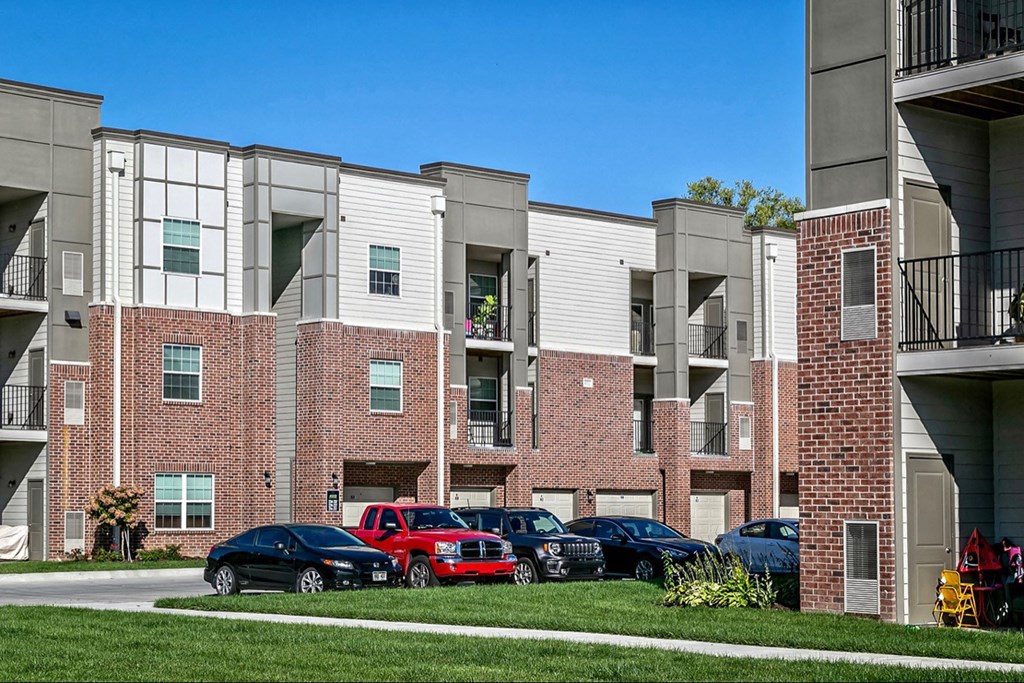 a brick and white apartment building with cars parked in front