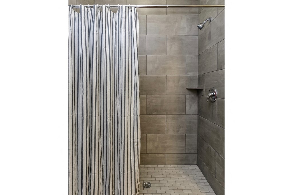 a shower with a striped shower curtain in a bathroom