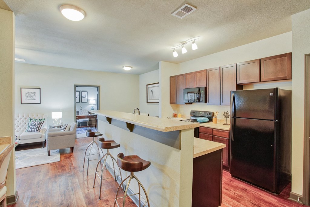 the view of a kitchen with a bar and a living room