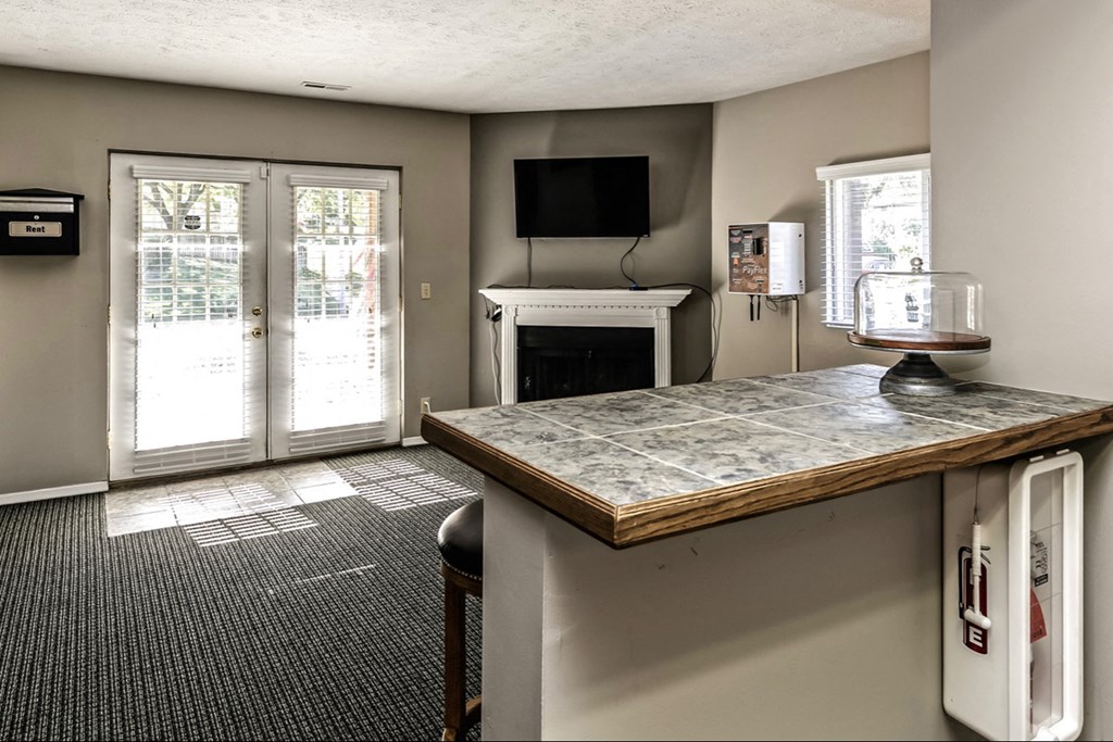 a living room with a fireplace and a kitchen with a bar and a tv