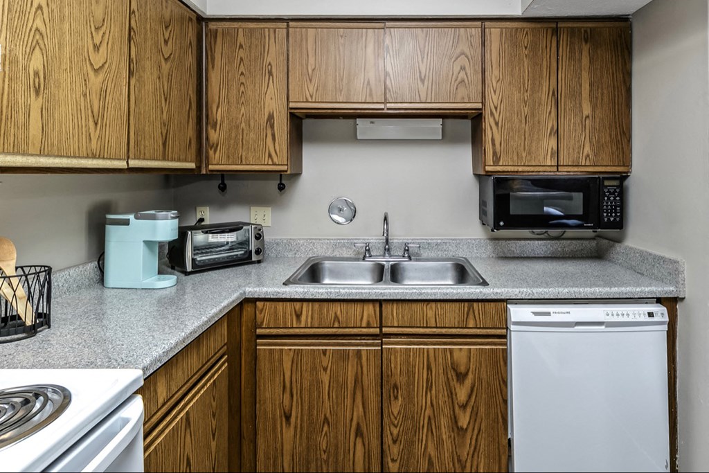 an empty kitchen with wooden cabinets and a sink and a stove