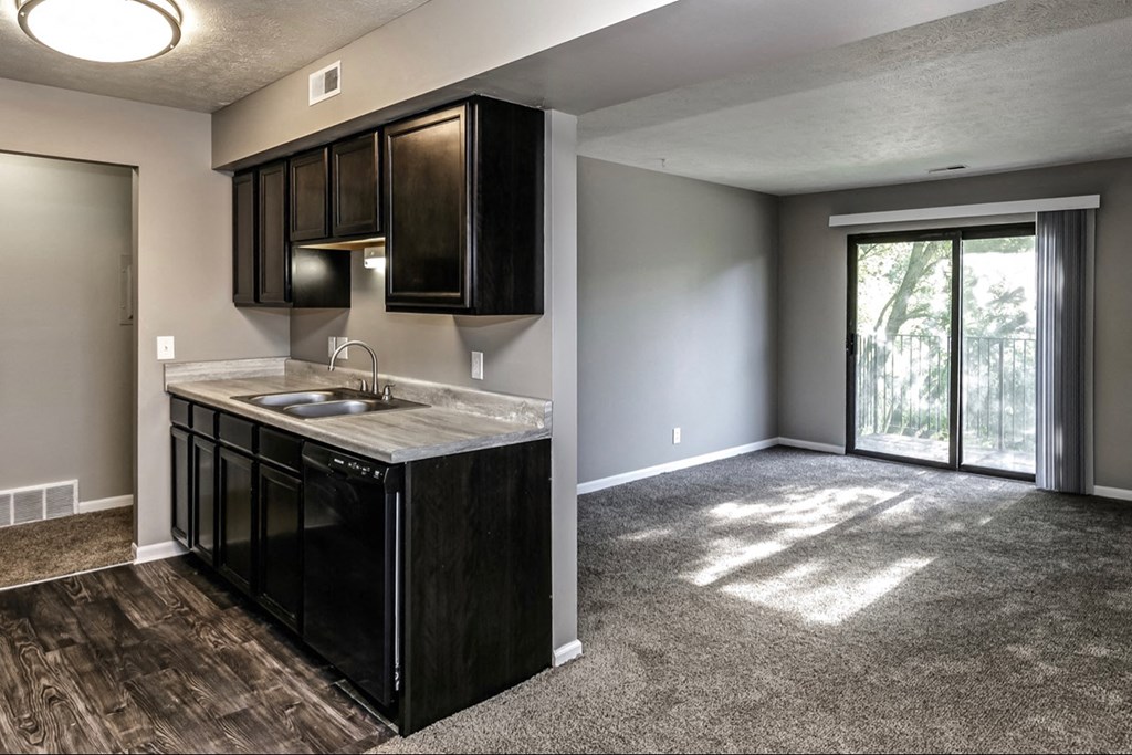 an empty living room with a kitchen and a sliding glass door