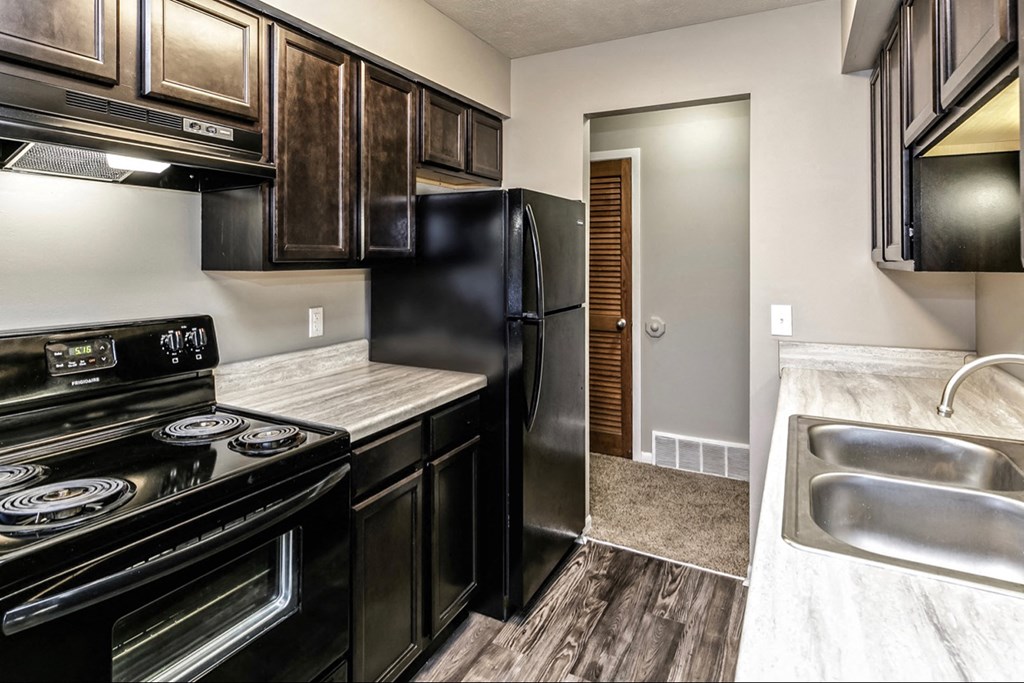 the kitchen of a home with black appliances and wood cabinets