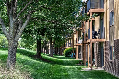 a row of apartment buildings with trees and green grass