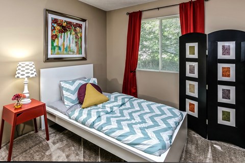 a bedroom with a bed with a blue and white bedspread and a red table