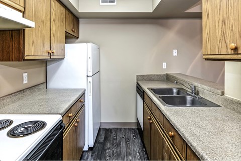 A kitchen with a white stove top oven, a white refrigerator, and a white dishwasher.
