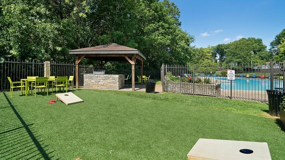 A backyard with a gazebo, a pool, and a disc golf hole.