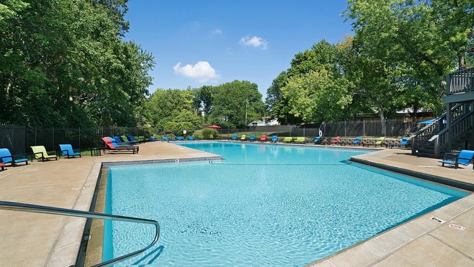 A large swimming pool surrounded by trees and lounge chairs.