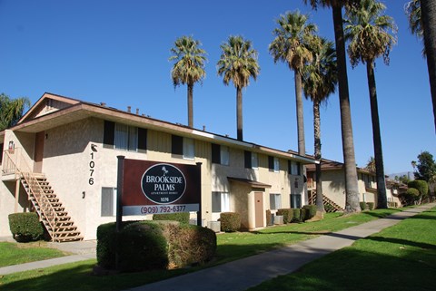 A brown sign in front of a building that says Brookside Palms.