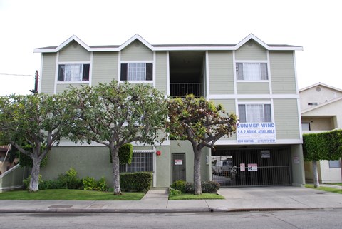A two story apartment building with a sign that says "Summer Wind" on it.