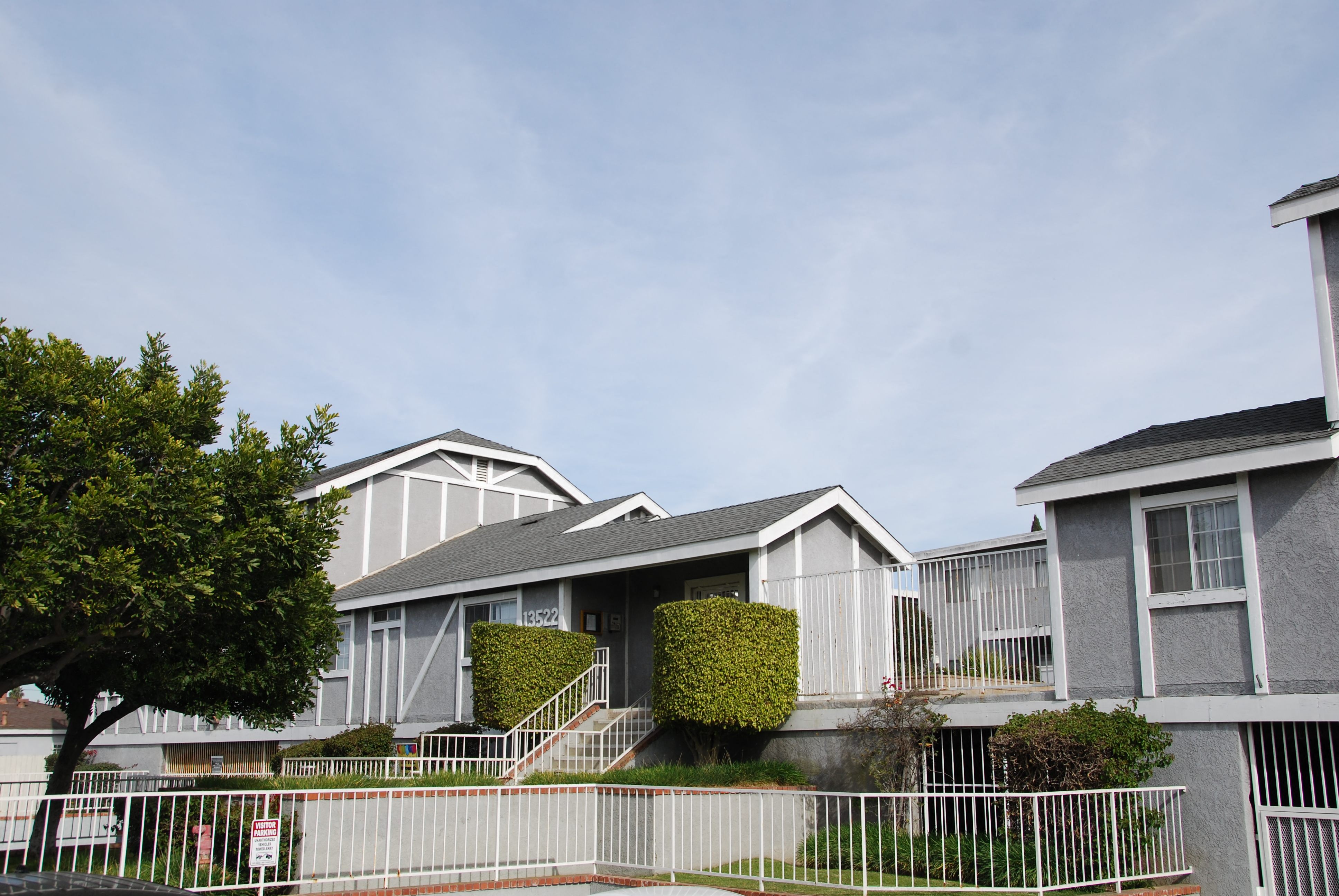 A row of houses with a white fence in front.