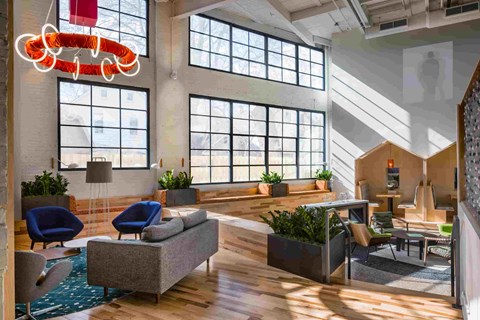 A modern office space with a large window, a blue chair, and a wooden floor.