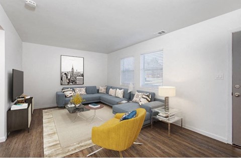 A living room with a grey couch, a yellow chair and a painting on the wall.