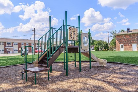 a playground with a slide and stairs in front of a building