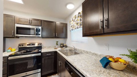 A kitchen with dark brown cabinets and granite countertops.