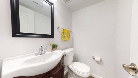 A bathroom with a white toilet, sink, and mirror.