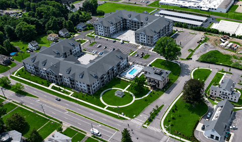 An aerial view of a large building with a pool in the middle of a grassy area.