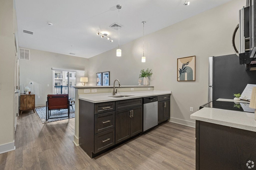 A kitchen with a white counter top and dark wood cabinets.