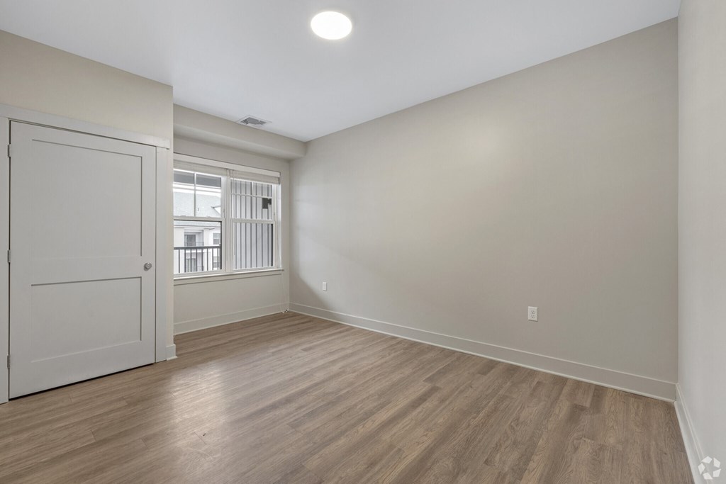 A room with a white door and wooden flooring.