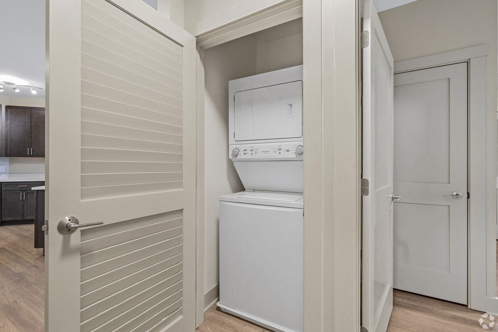 A white washing machine is in a small laundry room.