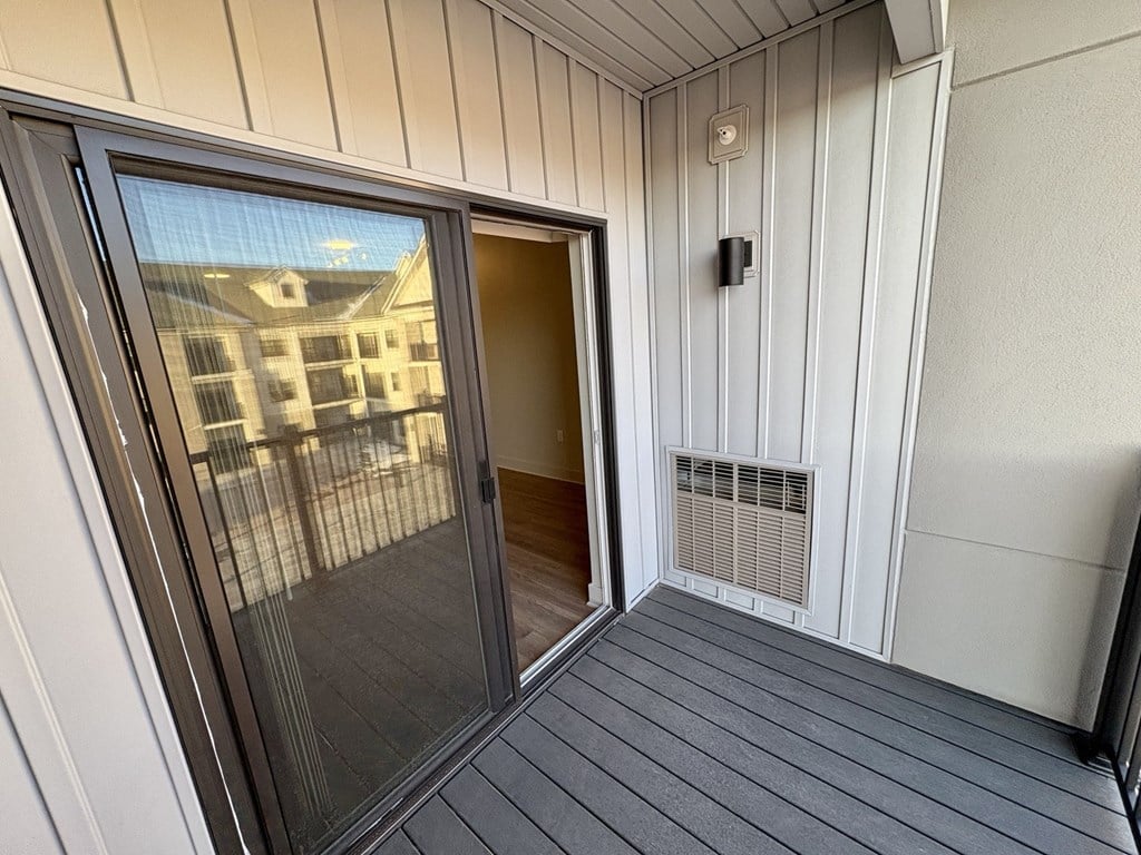 A balcony with a glass door and a heater vent.