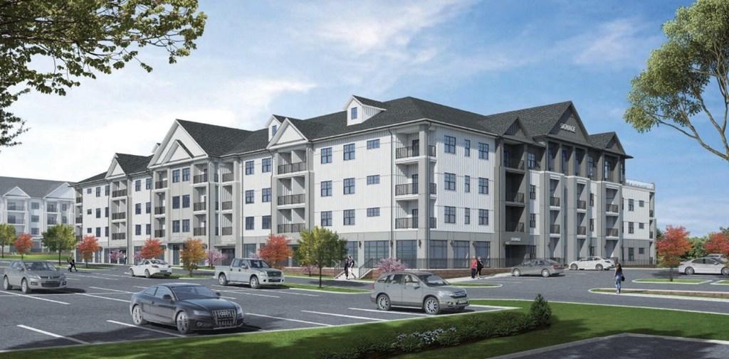 A large, modern apartment building with a parking lot in front.