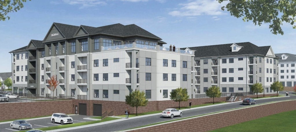 A large white building with a black roof and a parking lot in front.