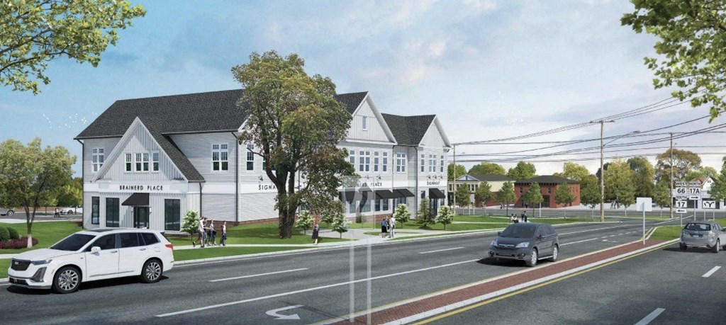 A white car is driving on a road next to a building with a sign that says