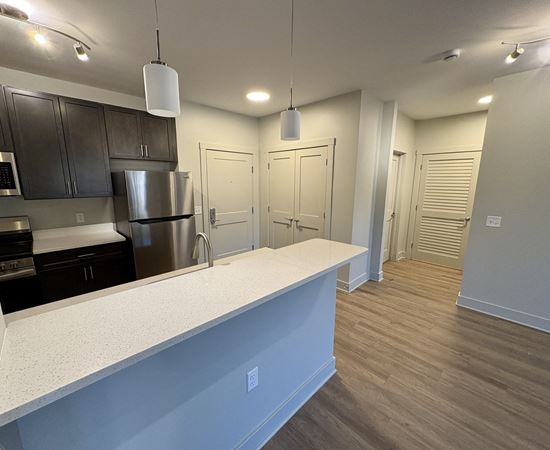 A kitchen with a white counter top and stainless steel appliances.