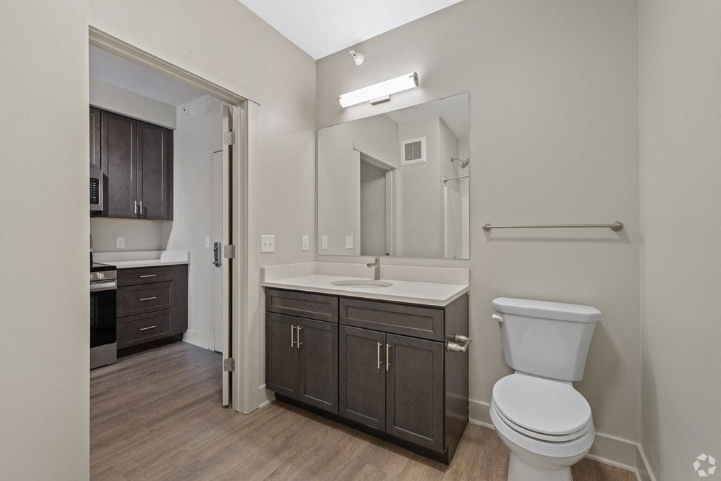 A bathroom with a toilet, sink, and mirror.