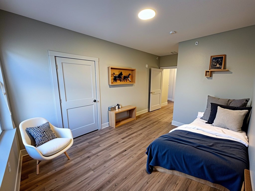A bedroom with a bed, chair, and artwork.