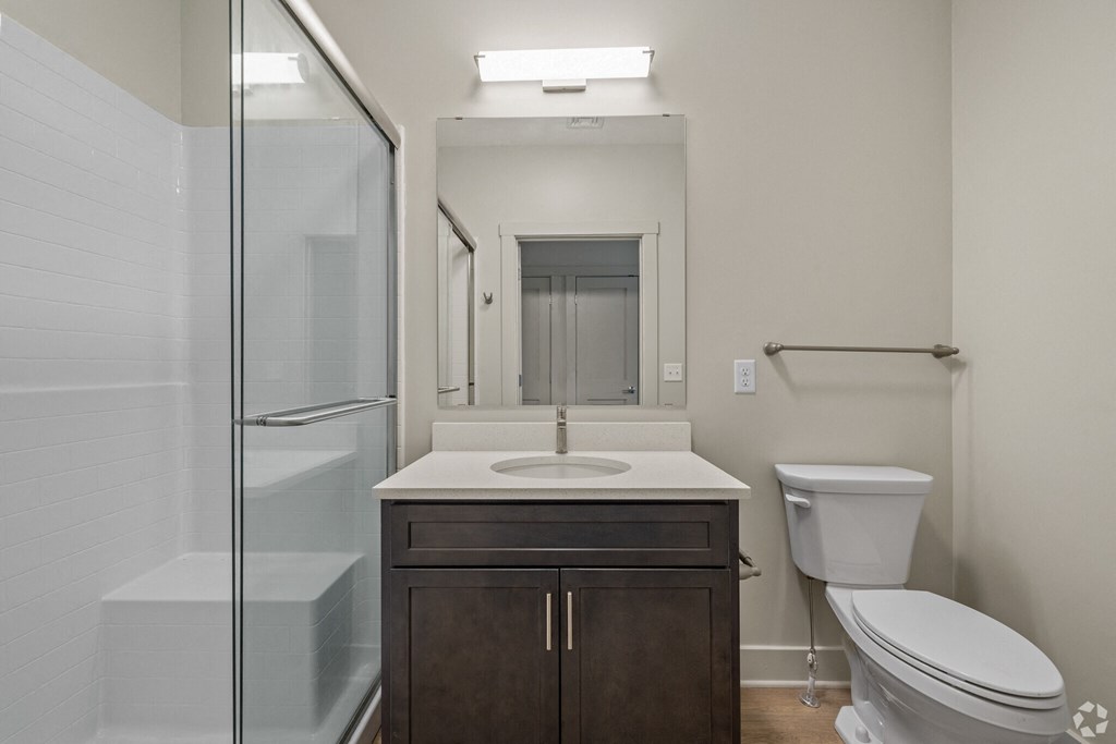 A bathroom with a toilet, sink, and shower.
