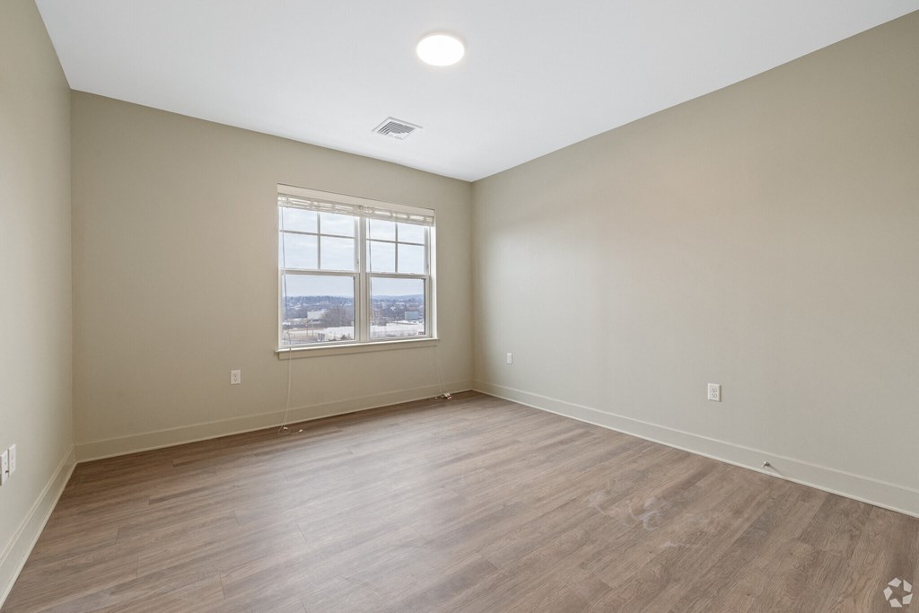 Empty room with a window and wooden flooring.